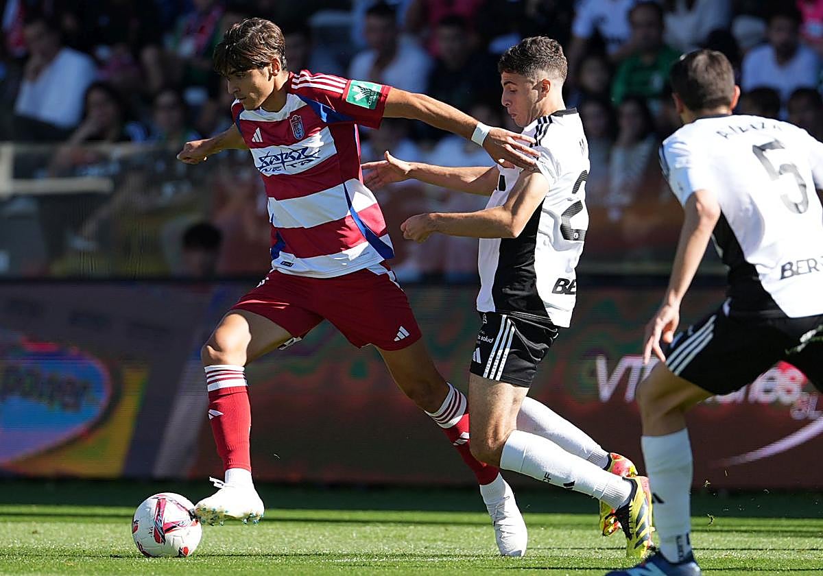 Gonzalo Villar avanza ante el acoso de los futbolistas del Burgos en El Plantío.