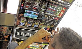 Un hombre se juega dinero en una tragaperras.