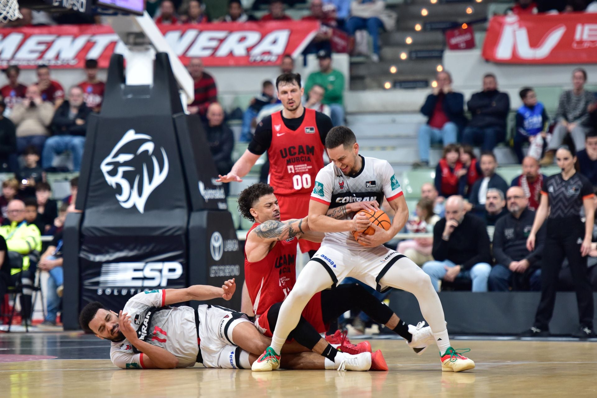 Scott Bamforth protege el balón ante la presión de Radebaugh, con Noua tendido en el parqué.