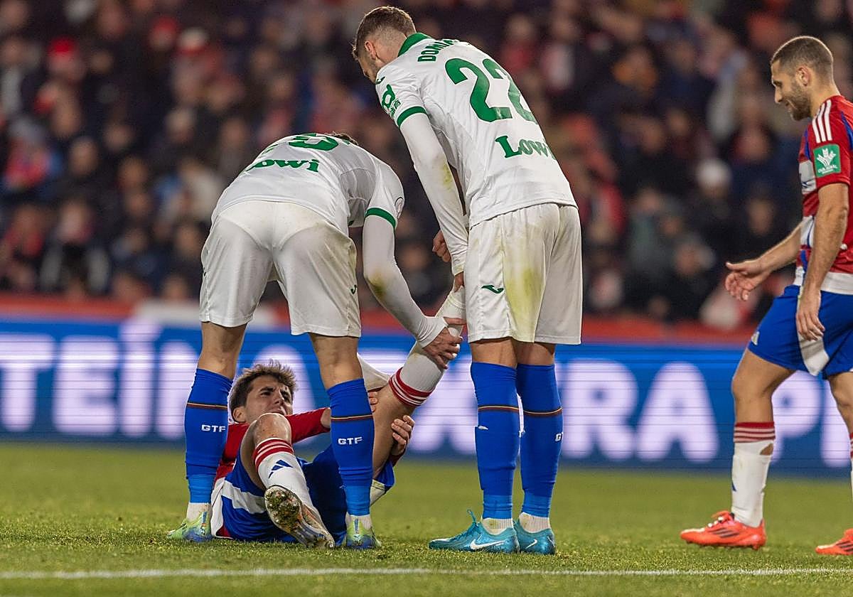 Manu Lama estira el gemelo izquierdo con la ayuda de dos futbolistas del Getafe.