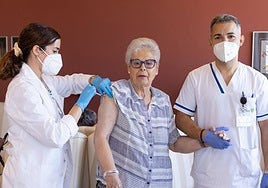 Una enfermera administra la vacuna de la gripe a una mujer en una residencia de mayores.