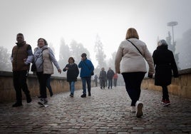 Paseantes por el Puente Romano, con la niebla.