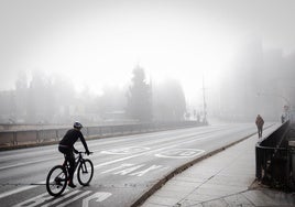 Un ciclista por el Puente Romano, con la niebla