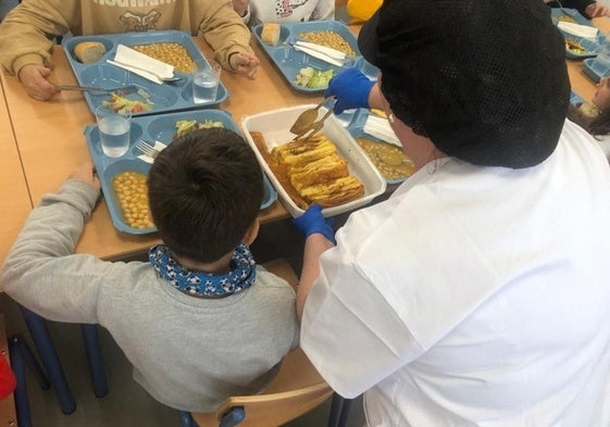 Una monitora sirve tortilla francesa en el comedor del CEIP 'Virgen del Río', de Huércal-Overa