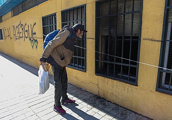 Antonio, una persona sin hogar, husmea el domingo por una ventana del local incendiado destinado a ser el nuevo albergue.