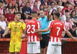 El colegiado Lax Franco dialoga con dos jugadores del Sporting en un encuentro de Segunda.