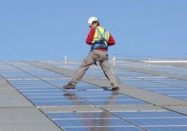 Un operario instala placas solares en un tejado.