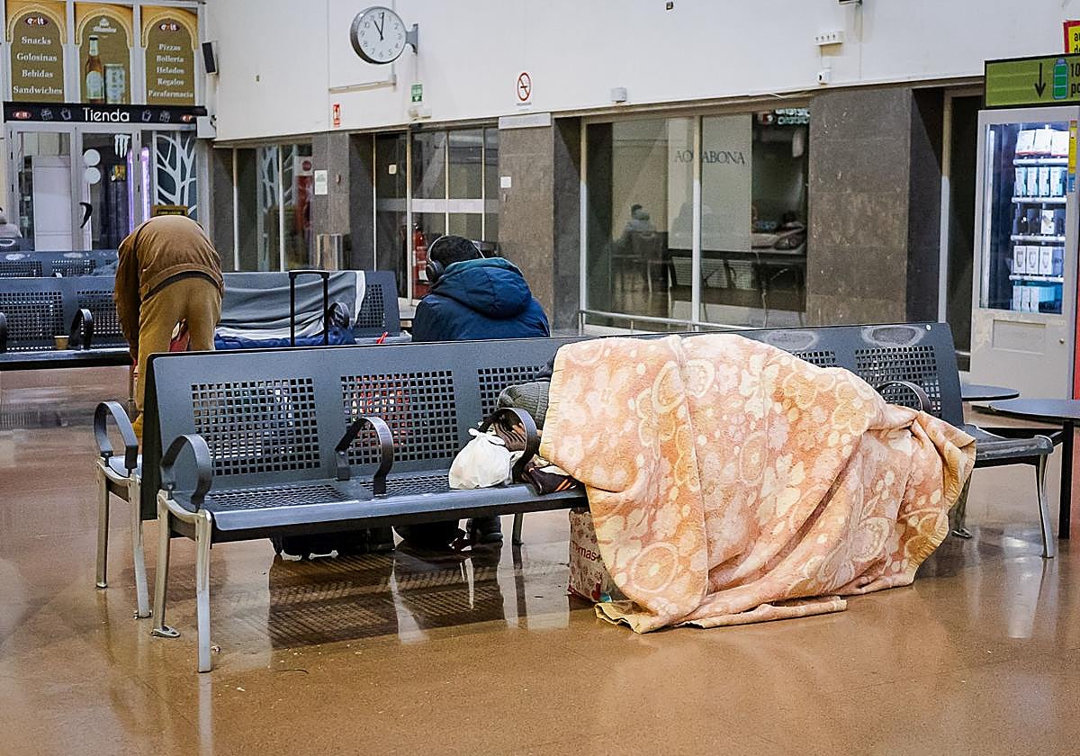 Una persona duerme en el interior de la estación de autobuses.