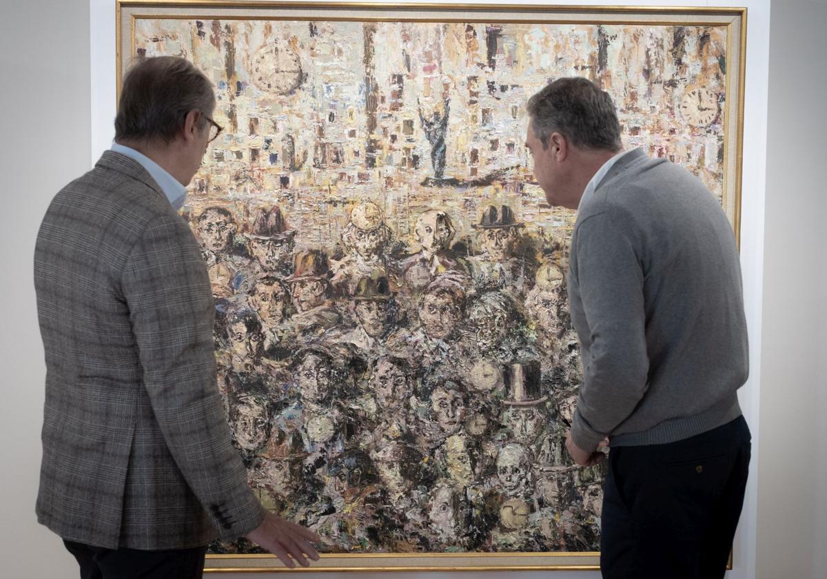 El comisario muestra a un visitante la obra 'Caras y cemento' con los integrantes de la Generación del 27.
