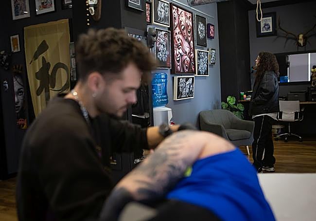 Exposición en Blackfemia mientras que uno de sus tatuadores trabaja en el brazo de uno de sus clientes.