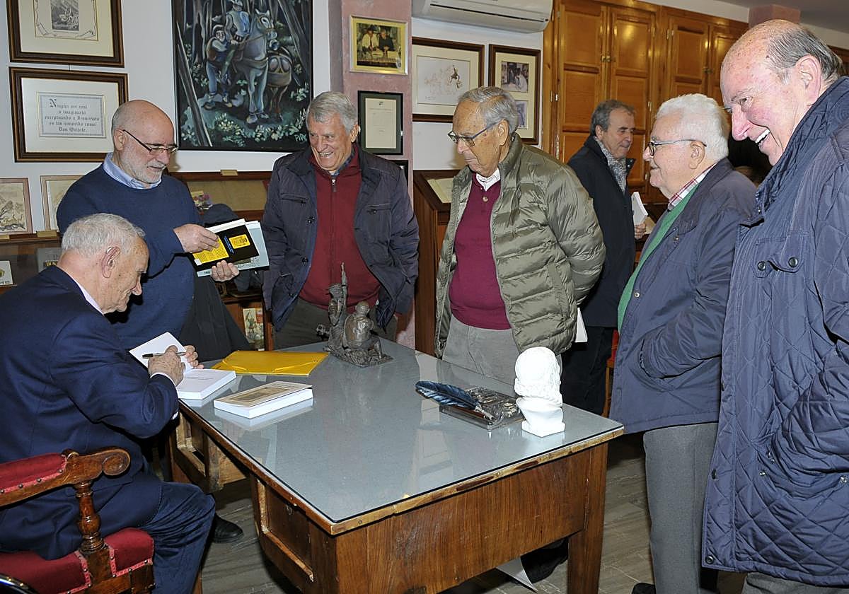 El orgiveño José Luis Puga Barroso sentado y firmando libros en la Biblioteca de Órgiva
