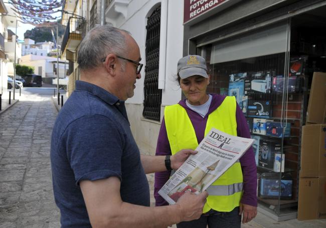 Francisco Muelas con el periódico IDEAL, junto a una operaria de la limpieza, en el estanco de su hijo.