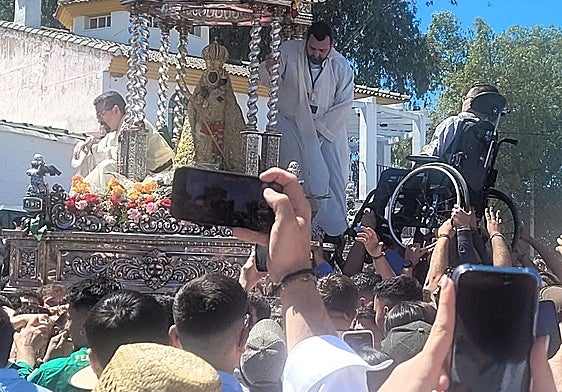 La Virgen va parando para recibir a personas aupadas por la masa.