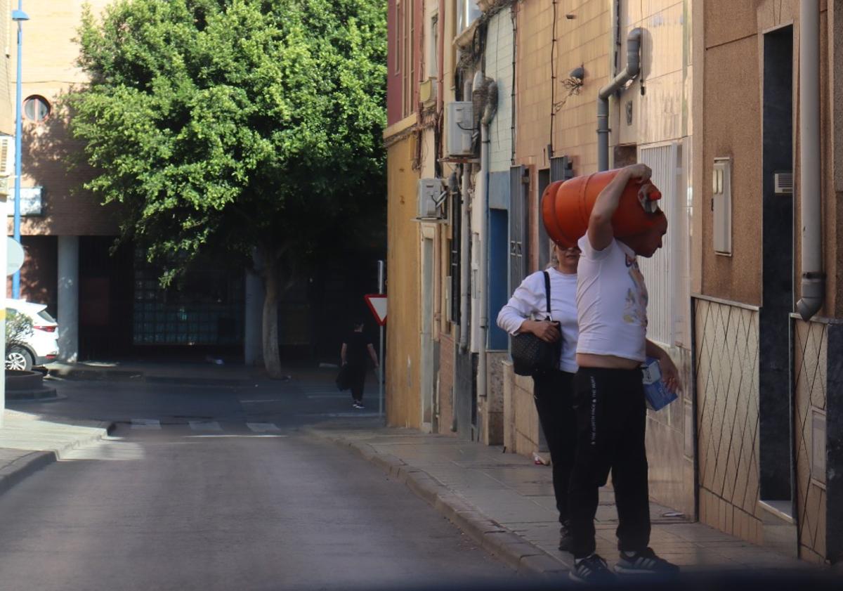 Imagen principal - Vecinos cargan con bombonas de butano mientras que los negocios del barrio paralizaron su actividad.