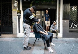 Un peluquero corta el pelo a un cliente en una calle de Granada durante el apagón.