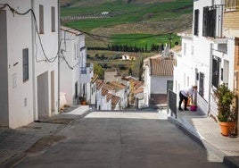 Una mujer baldea su vivienda en una de las empinadas calles de Santa Cruz del Comercio