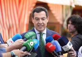 El presidente de la Junta, Juanma Moreno, atiende a los medios en la Feria de Sevilla.