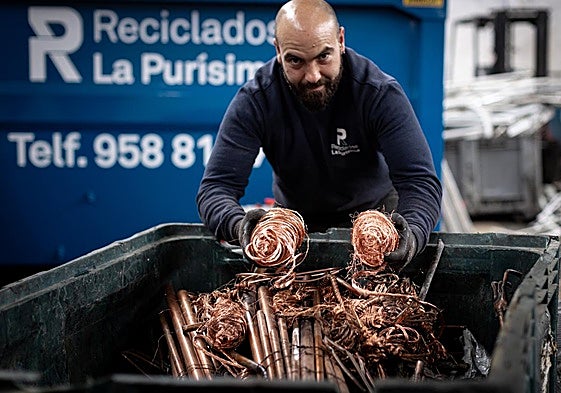 Un empleado de una empresa de reciclados enseña una muestra del cobre que recepcionan en la nave.