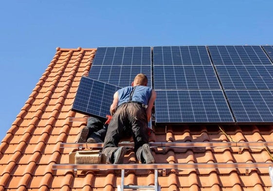 Un técnico instala una placa fotovoltaica en un tejado.