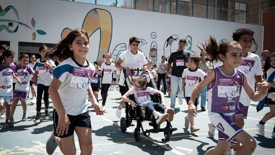 La atleta granadina María Pérez empuja el carro de Elenita rodeada de compañeros de la niña en el colegio Maristas, de Granada capital.