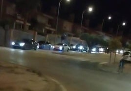 Hilera de vehículos saliendo de la urbanización de Otura.