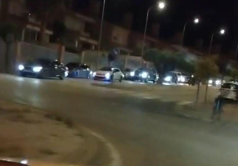 Hilera de vehículos saliendo de la urbanización de Otura.