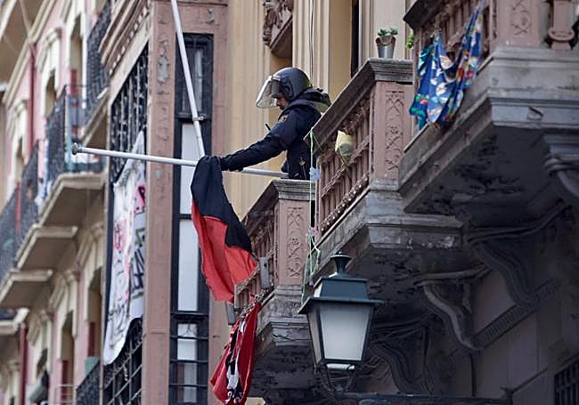 Un policía retira una bandera de la fachada del edificio.