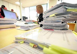 Expedientes pendientes y en tramitación sobre la mesa de una funcionaria.