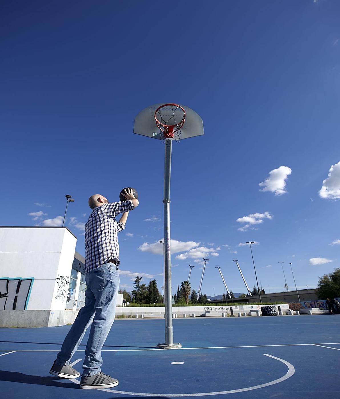 Un tipo intenta tirar en una de las altas canastas del botellódromo.