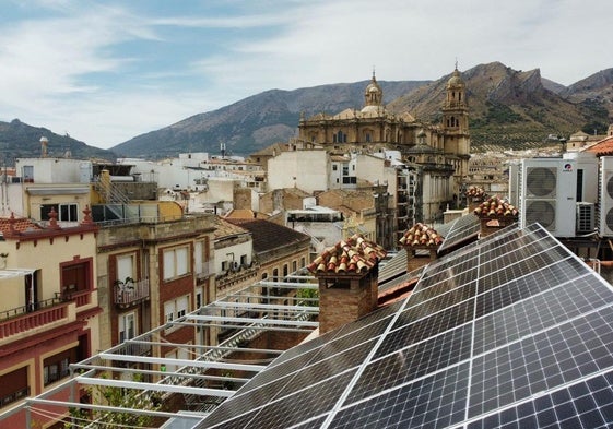 Dos instaladores trabajan en los paneles solares en el tejado de un edificio de viviendas.