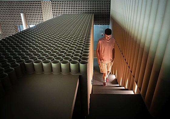 Trabajador de Cruz Roja accede a la planta superior de la nueva sede a través de la escalera, donde se aprecian las paredes de tubos de cartón industrial.