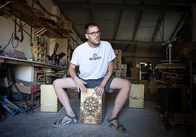 Daniel prueba el sonido de uno de los cajones fabricados en su taller.
