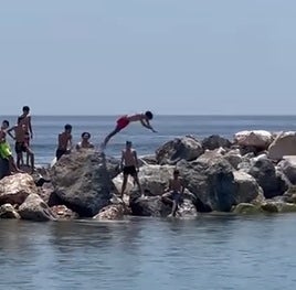 Niños se lanzan al agua desde el espigón de Motril.