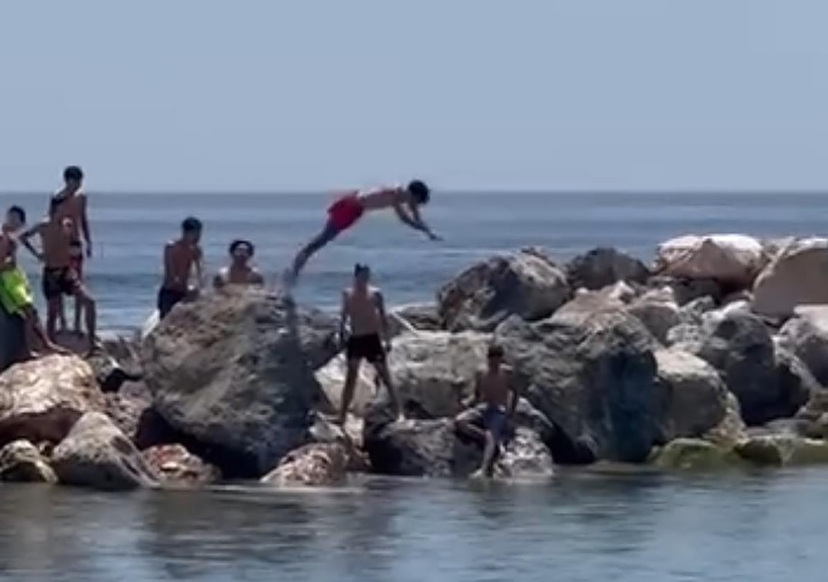 Niños se lanzan al agua desde el espigón de Motril.