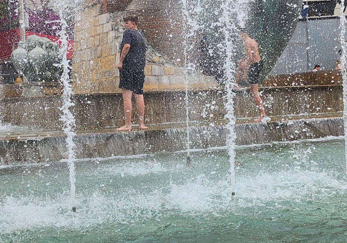 Jóvenes buscan refrescarse en la fuente de la plaza de la Constitución, en Jaén.