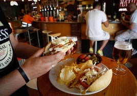 Un cliente disfruta de la bebida y la tapa.