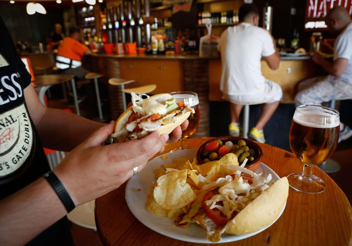 Un cliente disfruta de la bebida y la tapa.
