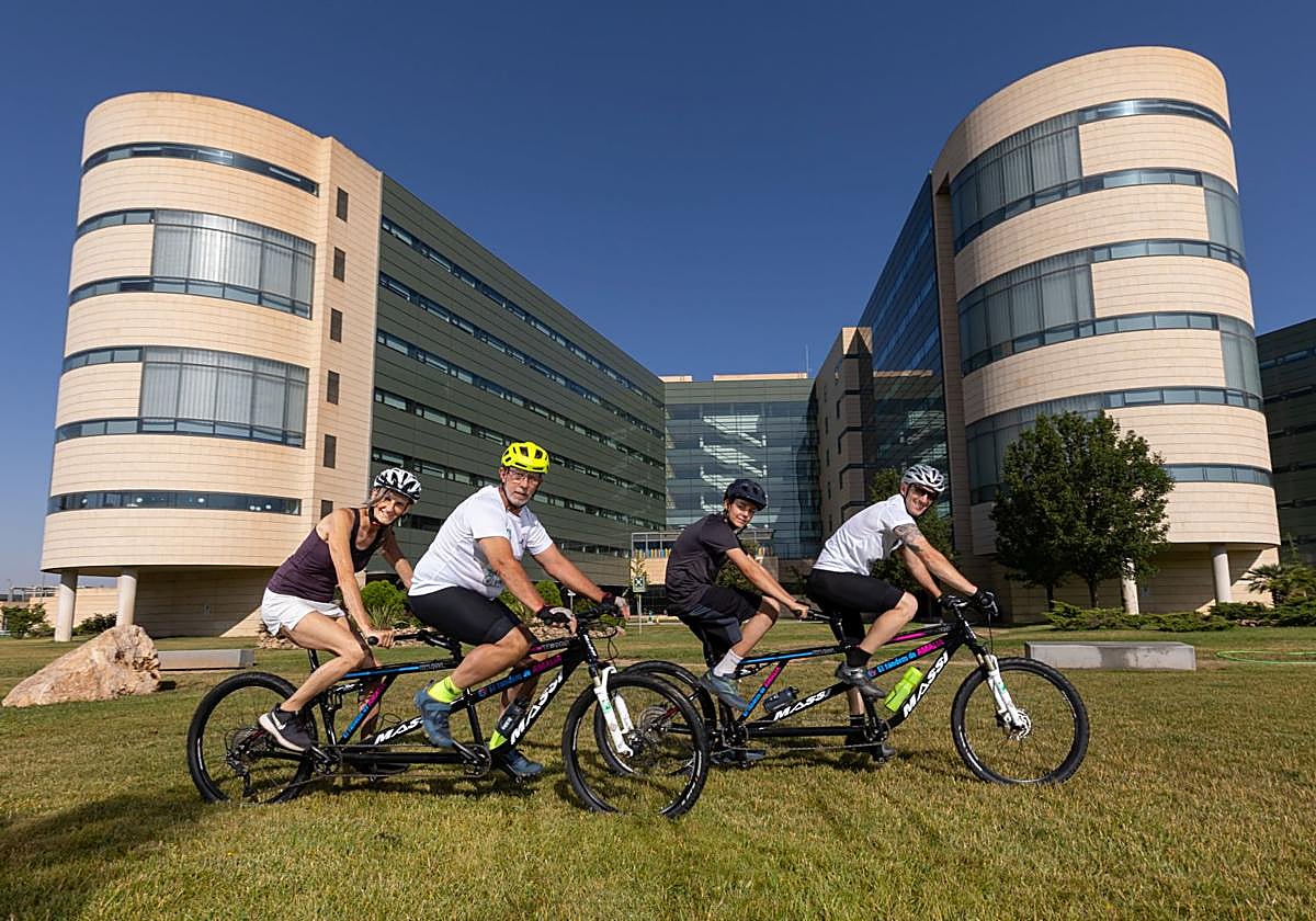 Dos voluntarios guían a una madre y un hijo supervivientes de cáncer de mama y leucemia en bicicletas para dos.