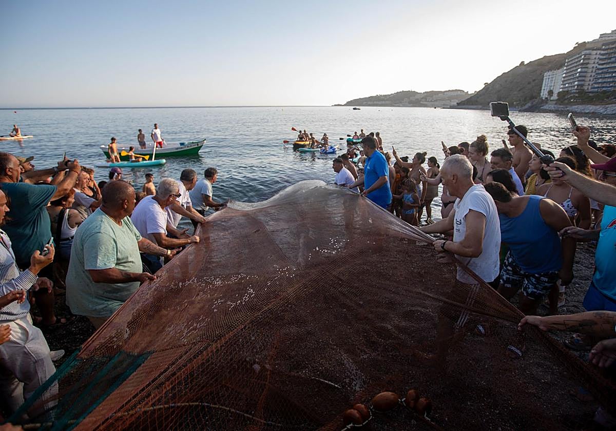 'Marengos' del barrio de Los Marinos tiran de la red durante la recreación del tiro del copo realizada ayer después de 40 años en la playa de la China de Almuñécar.