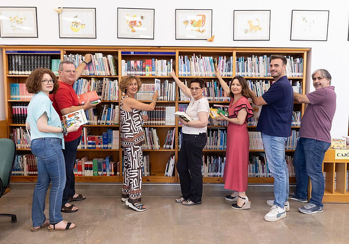 Concejales, bibliotecarios y miembros de la asociación de vecinos depositan los libros donados en las estanterías.