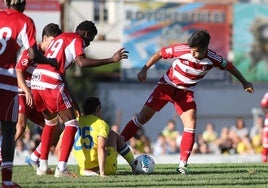 Los futbolistas del Granada intentan arrebatar el balón a uno del Cádiz a ras de césped.