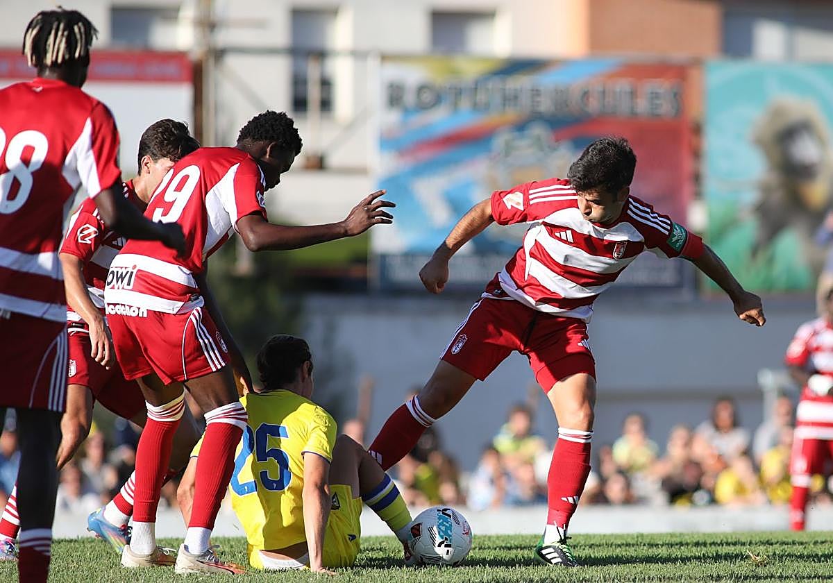 Los futbolistas del Granada intentan arrebatar el balón a uno del Cádiz a ras de césped.