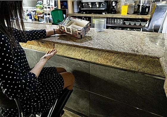 Una clienta muestra una caja colocada de forma temporal en un local afectado, así como la barra rota.