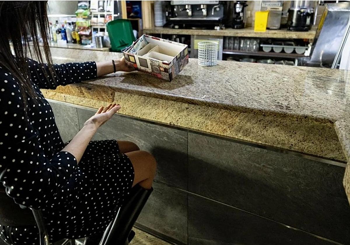 Una clienta muestra una caja colocada de forma temporal en un local afectado, así como la barra rota.