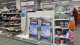 Tabla de planchar y tendederos de ropa bajo el letrero de sección de mujer.