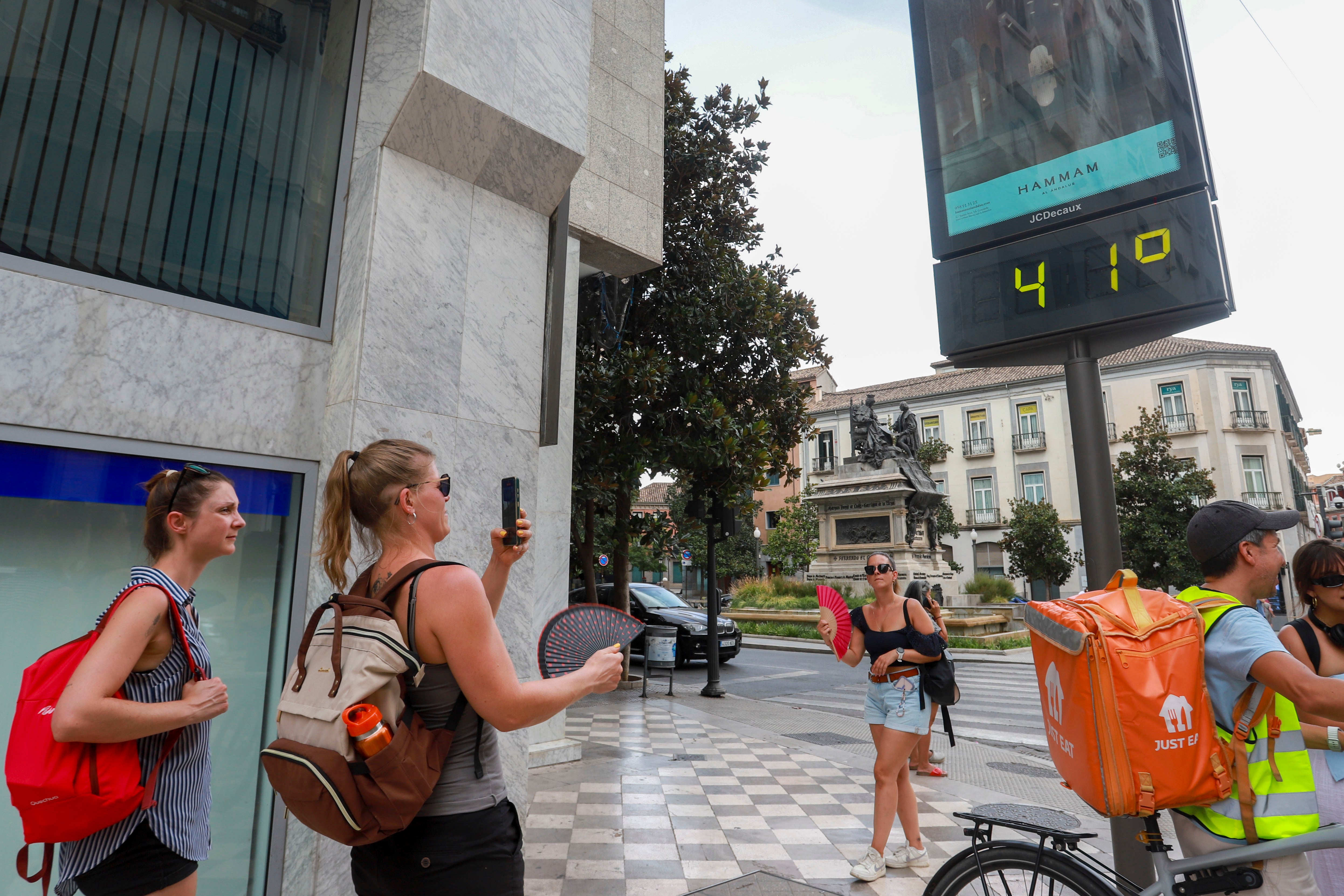 Dos chicas sacando una foto del termómetro de marquesina