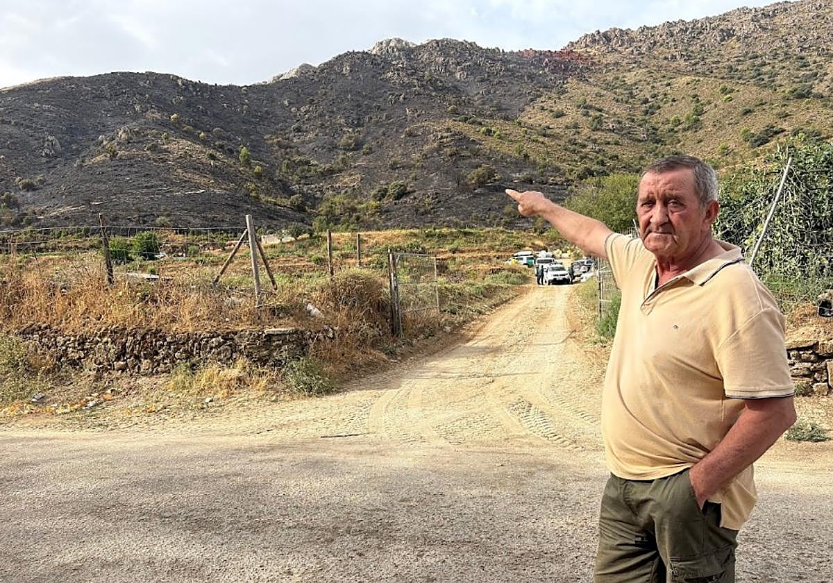Un vecino señala la zona quemada por el incendio.