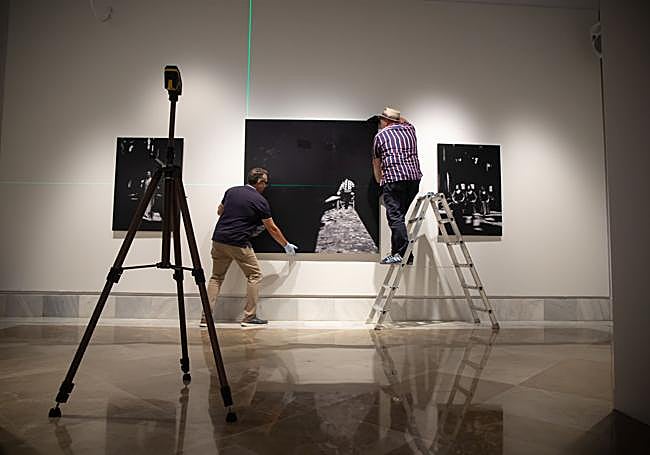 Operarios colocando una de las fotos de la exposición, que se podrá ver hasta el día 27.