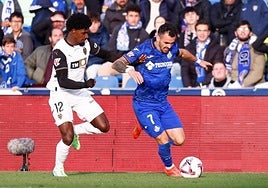Álex Sola conduce un balón perseguido por Thierry, del Valencia.