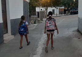 Las dos hermanas caminan por el pueblo con sus mochilas.